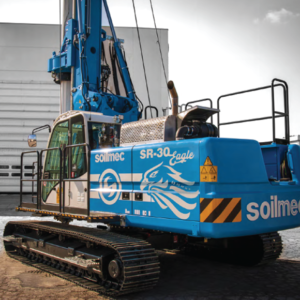 A backhoe, a large blue machine, is actively working on the ground.