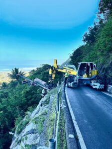 A construction vehicle equipped for foundation drilling parked along a mountain road, showcasing drilling and excavation capabilities.
